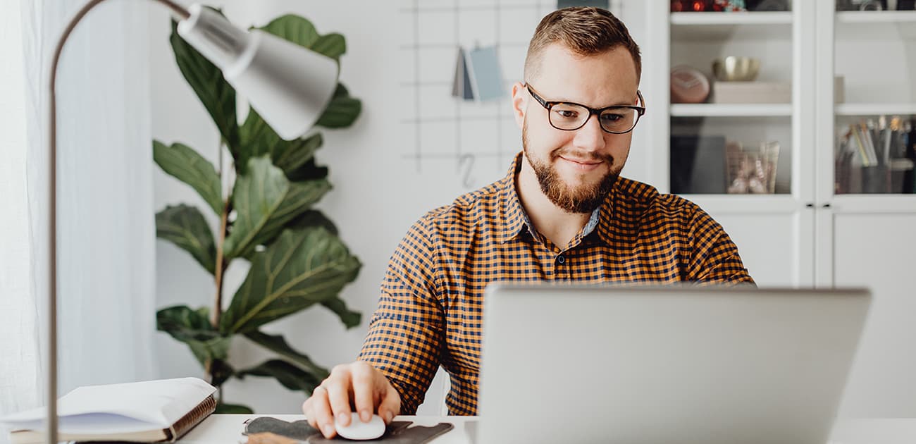 Man working on chatbot project on a laptop smiling.